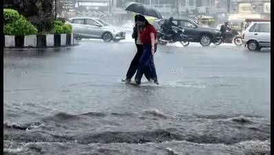 Light rain falling on an Indian city street with puddles and wet surfaces.