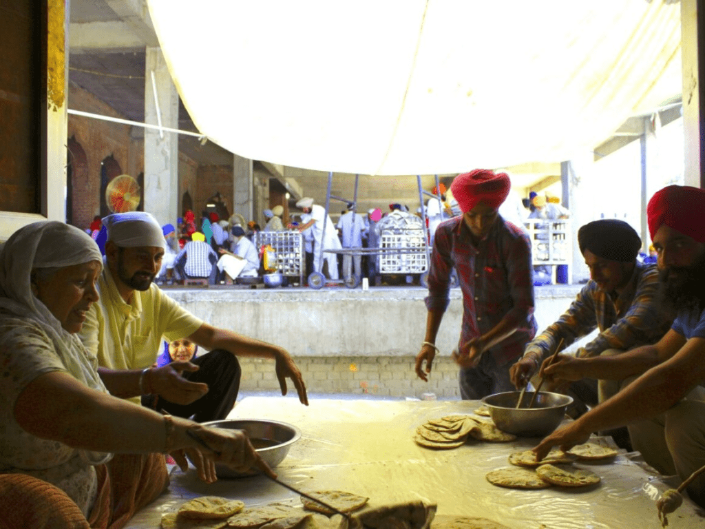 Gurdwara interior during Gurpurab observance, with devotees engaged in akhand path and kirtan around the Guru Granth Sahib for collective reflection.