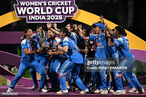 Indian Women's Cricket Team celebrating with the trophy after winning the 2025 ICC Women's Cricket World Cup, with Nallapureddy Shree Charani as part of the historic triumph.